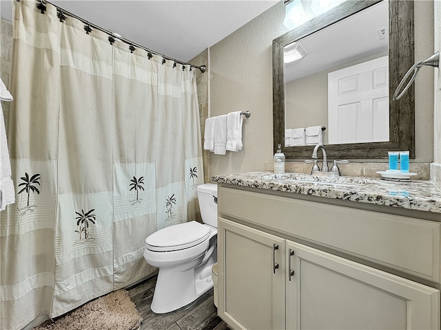 bathroom featuring walk in shower, vanity, a textured ceiling, wood-type flooring, and toilet