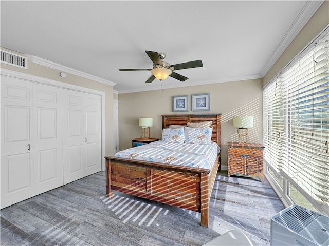 bedroom with ornamental molding, a closet, dark wood-type flooring, and ceiling fan