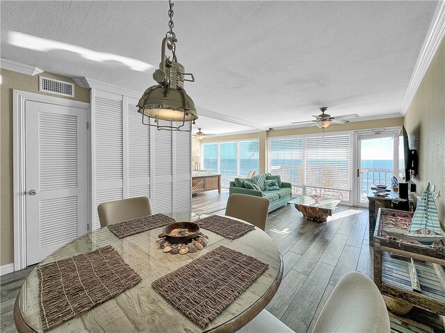 dining area featuring crown molding, a textured ceiling, and hardwood / wood-style flooring