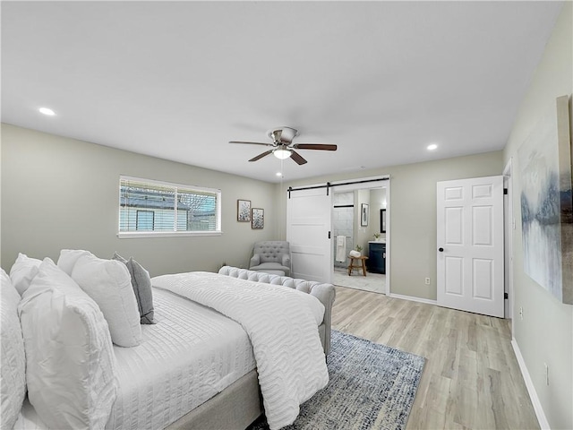 bedroom with a barn door, light wood-type flooring, recessed lighting, and baseboards