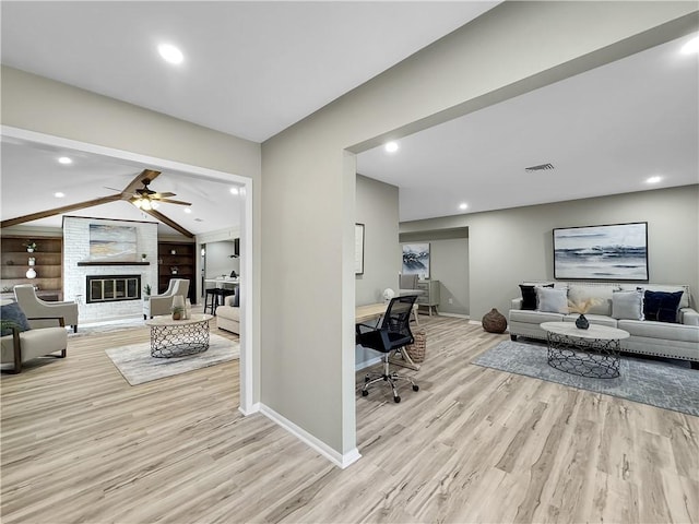 interior space featuring baseboards, visible vents, a glass covered fireplace, wood finished floors, and vaulted ceiling with beams