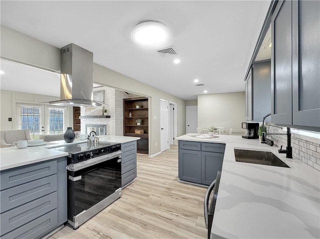 kitchen with island exhaust hood, visible vents, gray cabinetry, a sink, and range with electric cooktop