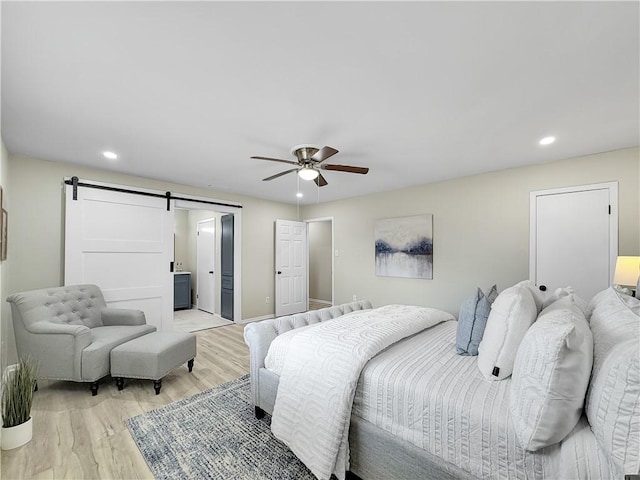 bedroom featuring a barn door, light wood-type flooring, a ceiling fan, and recessed lighting