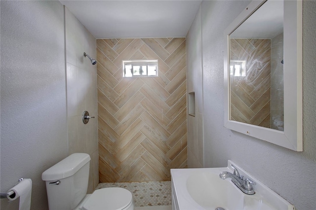 bathroom with sink, toilet, and a tile shower