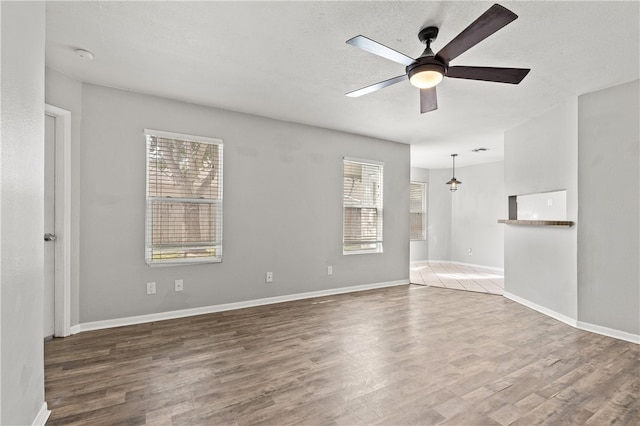 spare room featuring a textured ceiling, dark hardwood / wood-style flooring, ceiling fan, and plenty of natural light