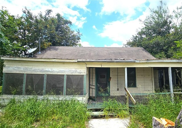 411 E Sarah St, Beeville, TX 78102 - rear view of property with roof with shingles, a sunroom, and concrete block siding