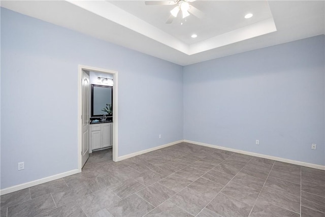 spare room featuring a raised ceiling and ceiling fan