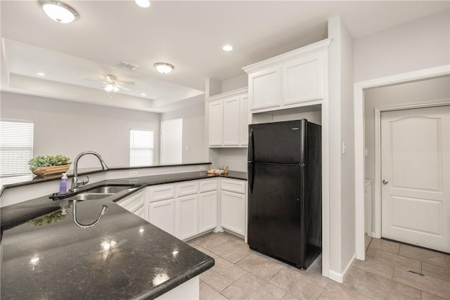 kitchen with kitchen peninsula, white cabinets, and black fridge