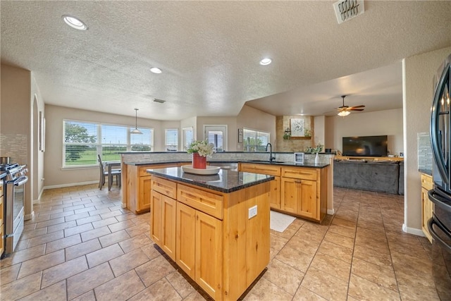 kitchen featuring stainless steel gas range, sink, decorative light fixtures, a center island, and kitchen peninsula