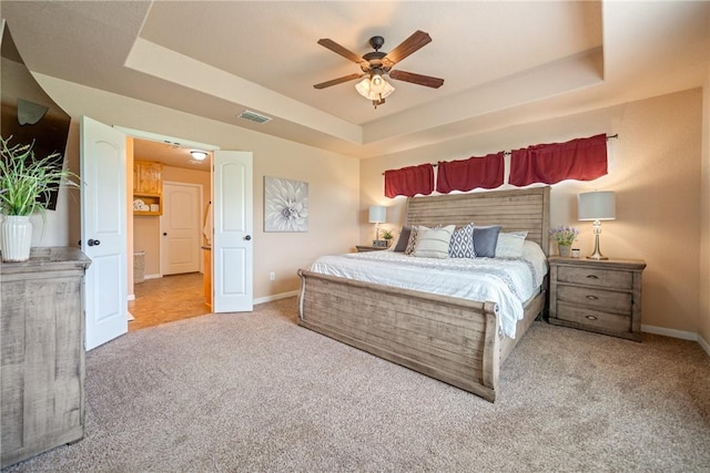 bedroom featuring ceiling fan, a tray ceiling, and carpet floors