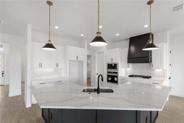 kitchen featuring visible vents, custom range hood, a sink, appliances with stainless steel finishes, and decorative backsplash