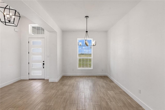 unfurnished dining area with light wood-style floors, baseboards, and a chandelier