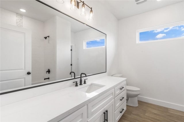 full bath featuring baseboards, a healthy amount of sunlight, wood finished floors, and vanity