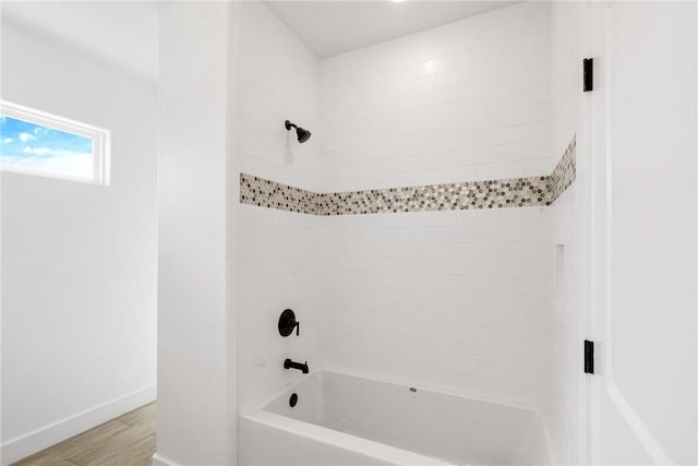 bathroom featuring tub / shower combination, baseboards, and wood finished floors