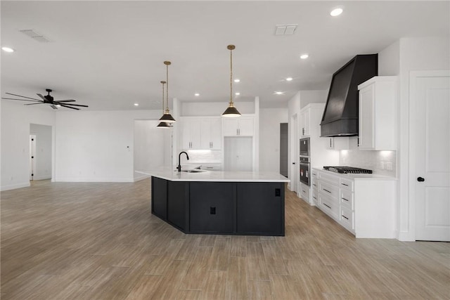 kitchen with premium range hood, a sink, light countertops, light wood-style floors, and appliances with stainless steel finishes