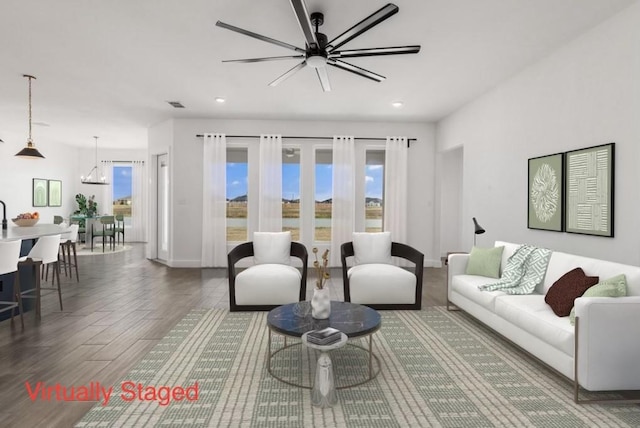 living area featuring visible vents, baseboards, recessed lighting, ceiling fan with notable chandelier, and wood finished floors