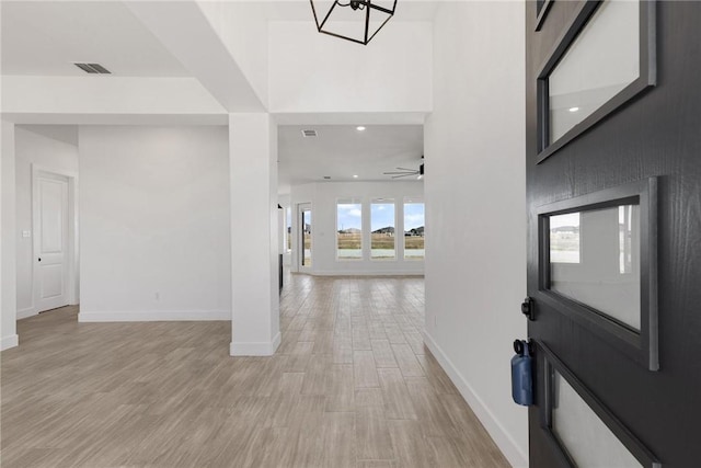 foyer featuring ceiling fan, visible vents, baseboards, and light wood-style flooring