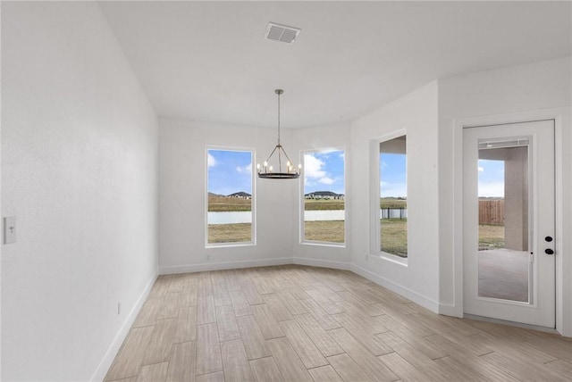 unfurnished dining area featuring baseboards, visible vents, light wood finished floors, a water view, and a chandelier