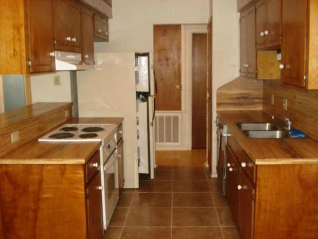 kitchen with dark tile patterned floors, sink, decorative backsplash, and electric range