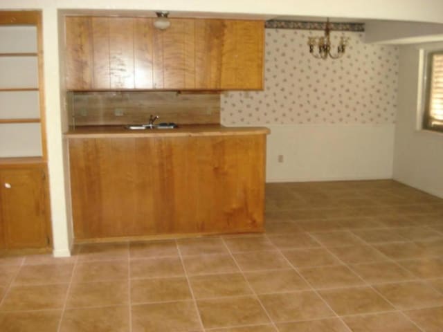 kitchen with pendant lighting, sink, light tile patterned floors, and backsplash