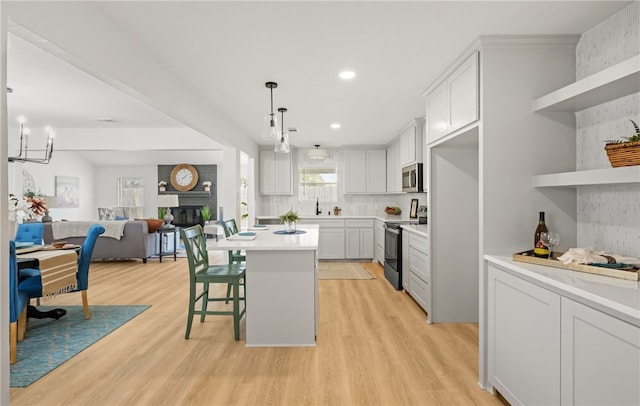 6905 Braesvalley Dr, Corpus Christi, TX 78413 - kitchen featuring range with electric cooktop, stainless steel microwave, open shelves, open floor plan, and light wood-type flooring
