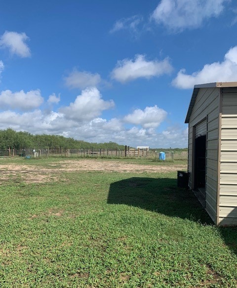 view of yard with a shed and a rural view