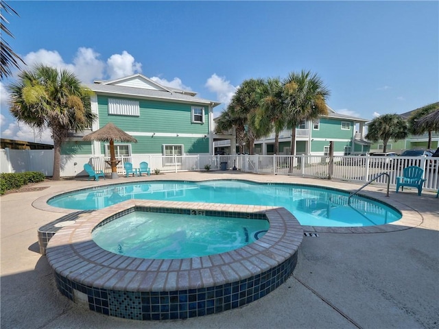 view of pool featuring fence, a patio area, and a pool with connected hot tub