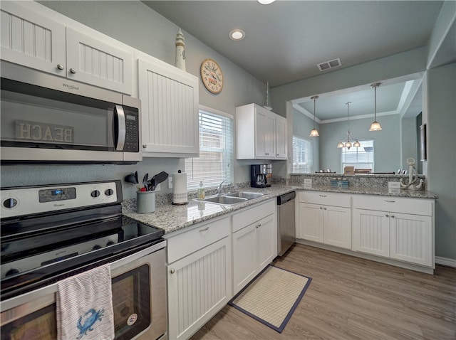 kitchen with stainless steel appliances, white cabinetry, sink, ornamental molding, and light hardwood / wood-style flooring