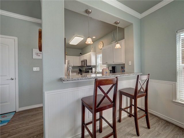 kitchen with a wealth of natural light, kitchen peninsula, stainless steel appliances, and white cabinets