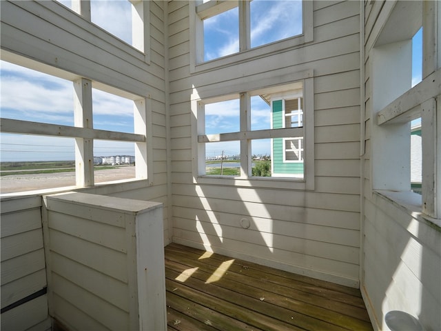 interior space with hardwood / wood-style floors, plenty of natural light, and wood walls