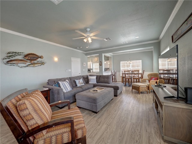 living room with ceiling fan with notable chandelier, crown molding, and light hardwood / wood-style flooring