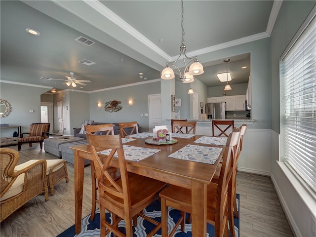 dining space with ceiling fan with notable chandelier, light hardwood / wood-style floors, and crown molding