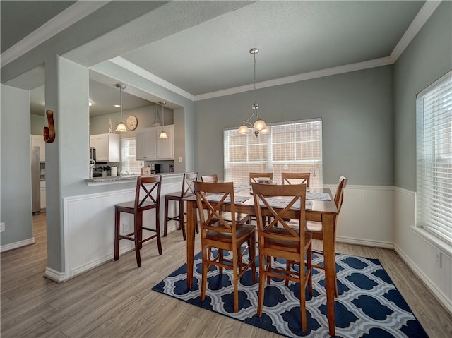 dining area featuring ornamental molding, a notable chandelier, and light hardwood / wood-style floors