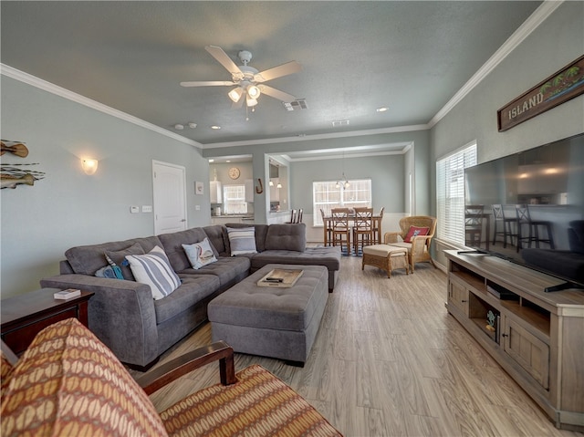 living room featuring ornamental molding, light wood-type flooring, ceiling fan with notable chandelier, and a textured ceiling