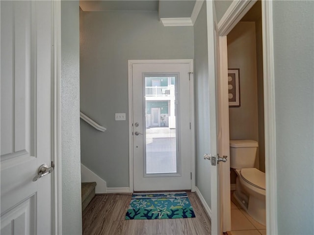 doorway with wood finished floors, stairway, and baseboards