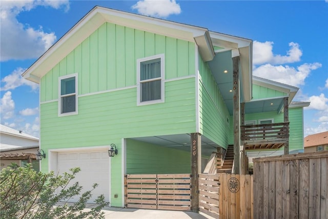 view of front facade with board and batten siding, fence, a garage, and stairs