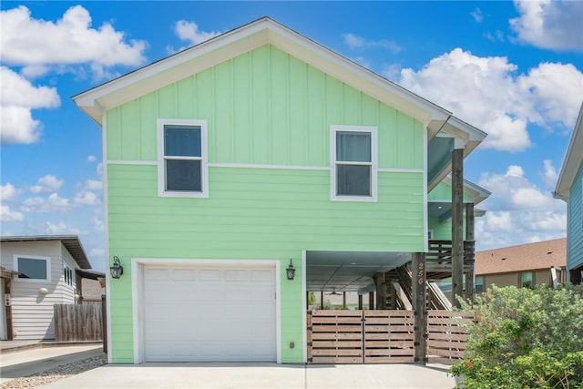 beach home featuring board and batten siding, an attached garage, concrete driveway, and stairs
