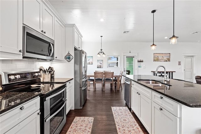 kitchen featuring stainless steel appliances, white cabinets, a sink, and decorative backsplash