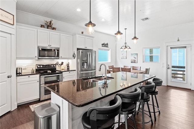 kitchen with visible vents, a sink, appliances with stainless steel finishes, dark wood-type flooring, and decorative backsplash
