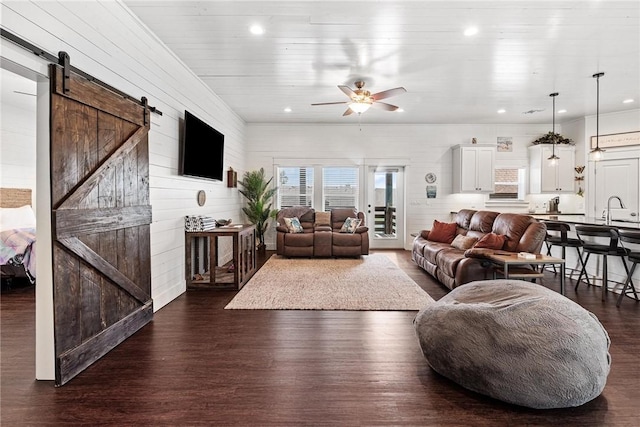 living room featuring recessed lighting, dark wood-type flooring, a barn door, and a ceiling fan