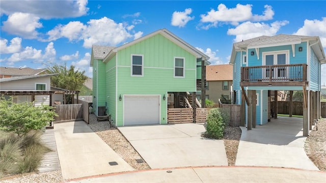 coastal inspired home with a garage, board and batten siding, fence, stairway, and driveway