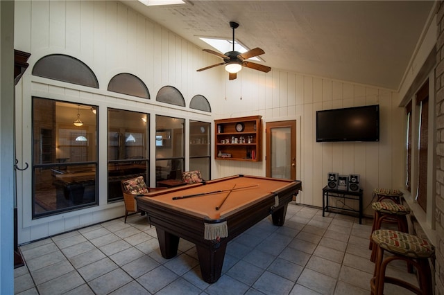 rec room featuring wood walls, pool table, lofted ceiling with skylight, ceiling fan, and light tile patterned floors