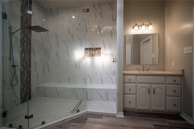 bathroom featuring wood-type flooring, vanity, and a tile shower