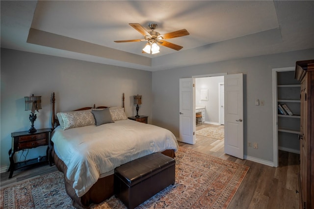 bedroom featuring wood-type flooring, ceiling fan, and a raised ceiling