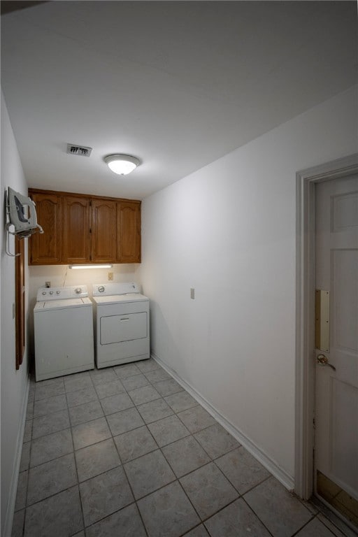 clothes washing area with cabinets, washing machine and dryer, and light tile patterned floors