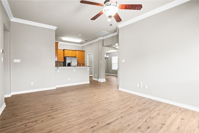 unfurnished living room featuring light wood-type flooring, ceiling fan, and crown molding