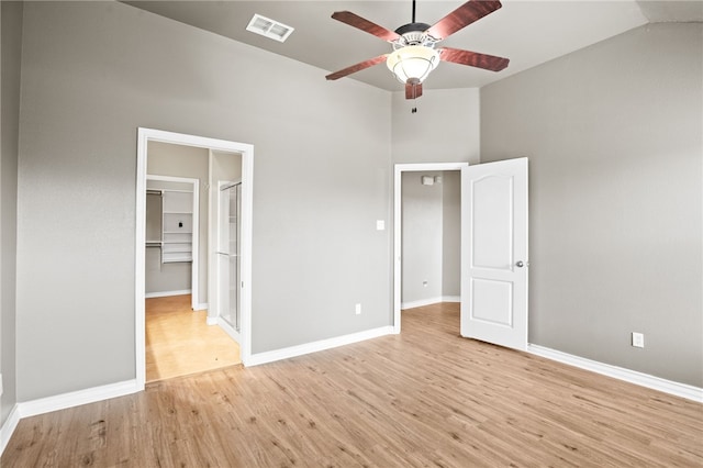 unfurnished bedroom with vaulted ceiling, ceiling fan, light hardwood / wood-style flooring, and a spacious closet