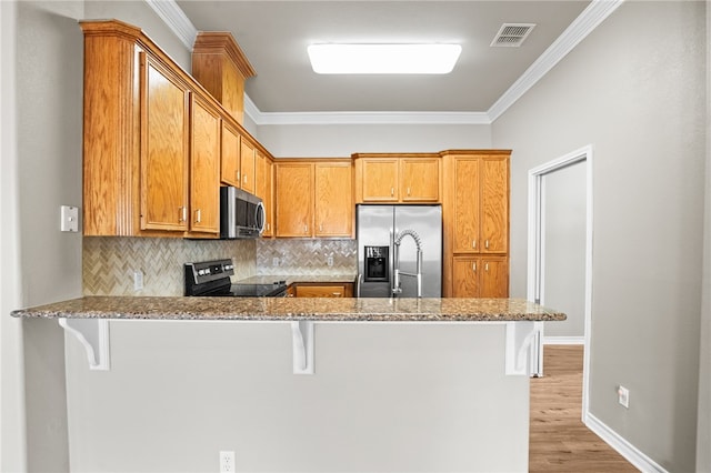 kitchen featuring ornamental molding, kitchen peninsula, stainless steel appliances, and light stone countertops