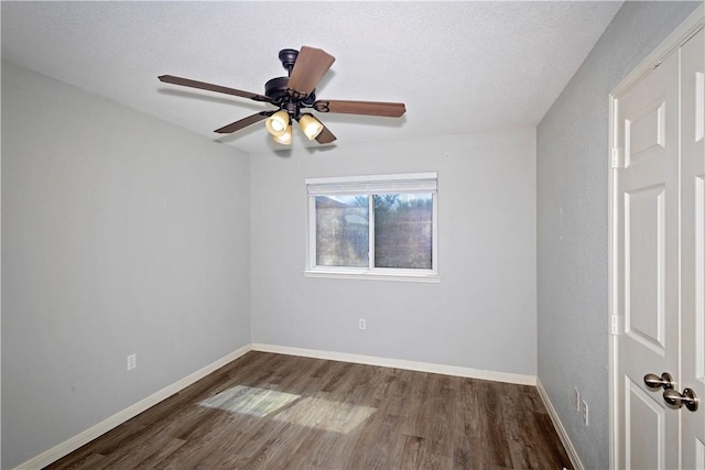 empty room featuring ceiling fan, dark wood-type flooring, and a textured ceiling