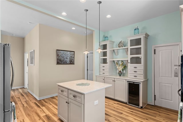 kitchen featuring stainless steel fridge, wine cooler, light wood-type flooring, decorative light fixtures, and white cabinets